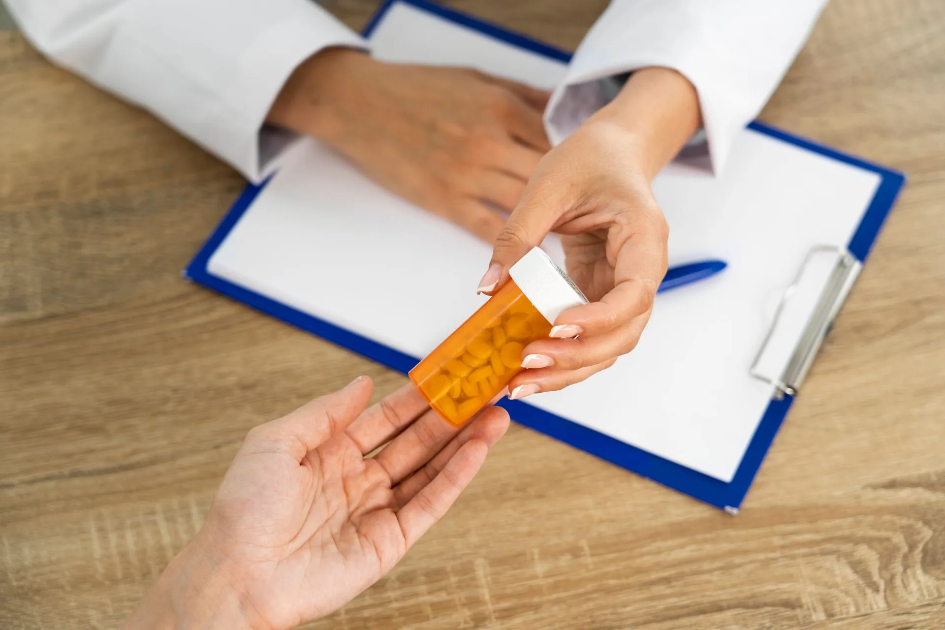 Pharmacist handing an orange prescription pill bottle to a patient