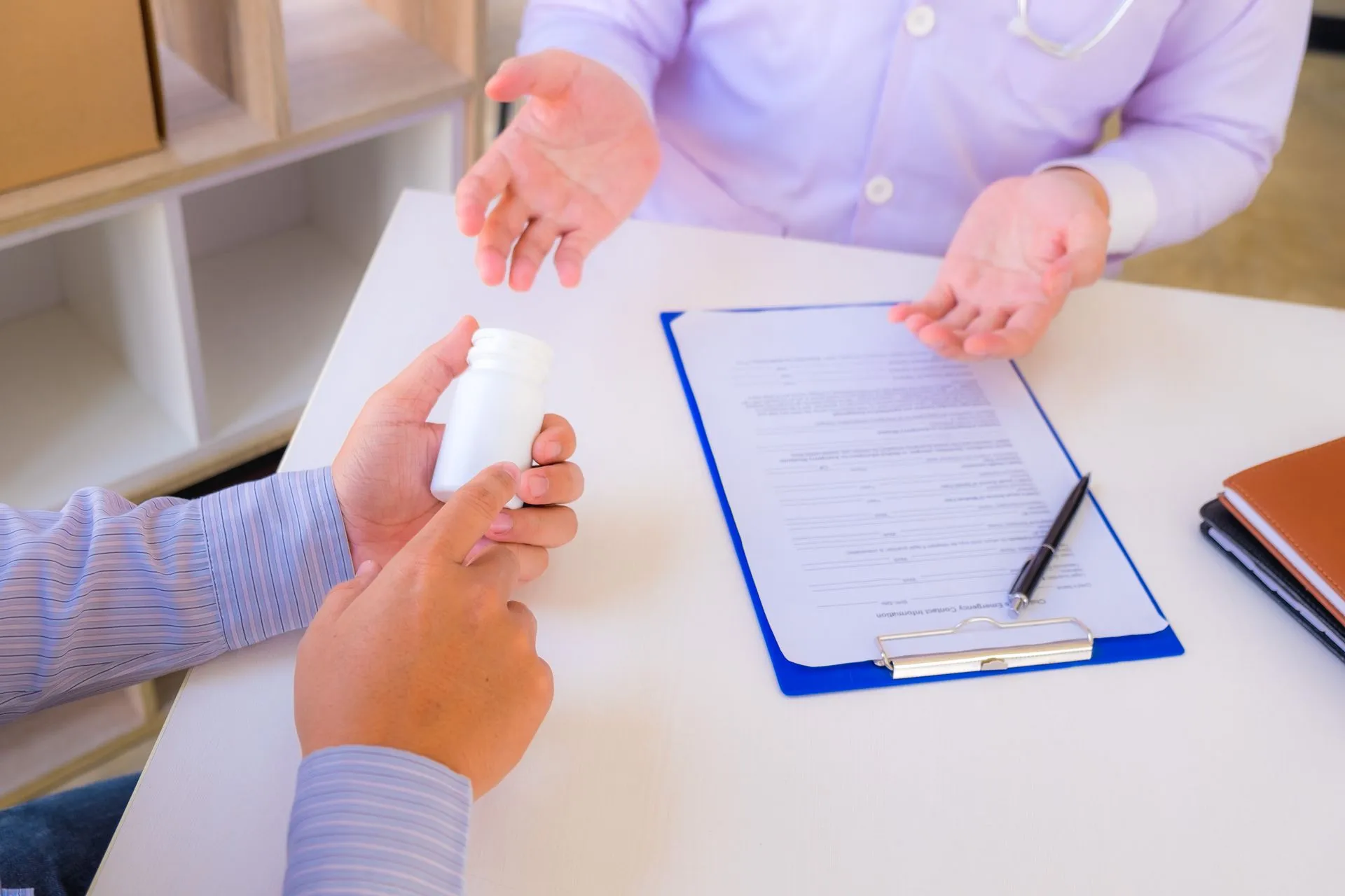 Patient holding a pill bottle while discussing a prescription with a doctor at a desk